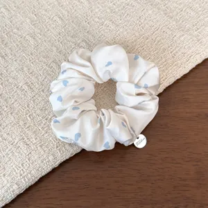 Close-up of sweet Korean pleated scrunchie with blue heart print and metal charm.