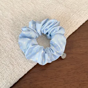 Detailed close-up view of the light blue polka dot hair scrunchie with sweet ruffles.