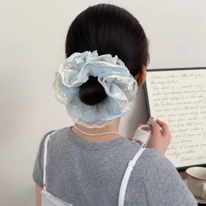 Primer plano de un coletero de flores azul suave con encaje blanco para peinados elegantes.