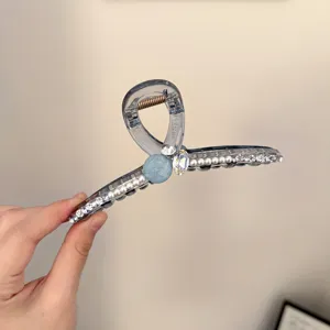 Vue détaillée de la pince à cheveux strass et perles, design transparent, maintien sûr.