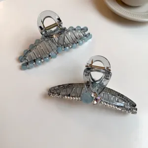 Gros plan détaillé d'une pince à cheveux grise transparente ornée de strass et de perles.