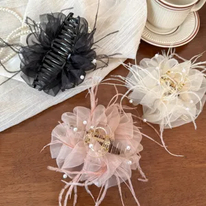 Close-up detail of luxury sheer mesh feather hair claw clip with faux pearls, elegant hair styling accessory.