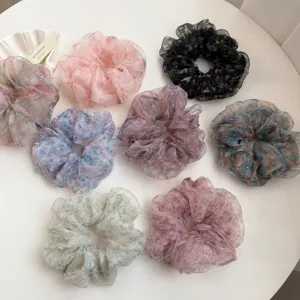 Close-up detail of colorful floral organza hair scrunchies with shiny rhinestones.