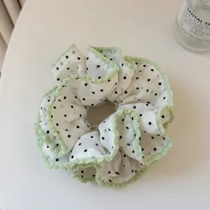 Sweet polka dot hair scrunchie with green ruffles, soft fabric hair tie for daily hairstyles.