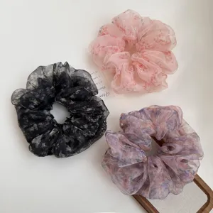 Close-up detail of fluffy organza rhinestone hair scrunchie, floral print design.