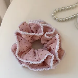 Close-up detail of a sweet pink polka dot hair scrunchie featuring elegant white ruffled edges.