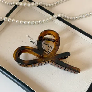 Elegante molletta per capelli in acrilico tartarugato marrone con design cavo incrociato.