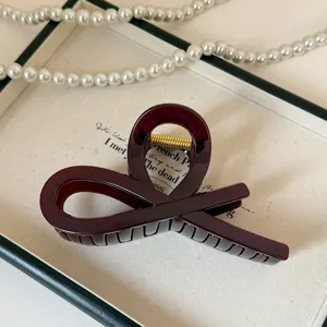 Elegante molletta per capelli in acrilico rosso scuro con design intagliato a croce.