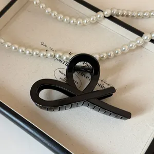 Dettaglio molletta per capelli in acrilico nero, elegante design incrociato per acconciature.