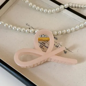 Primo piano del dettaglio della molletta per capelli rosa acrilico con molla dorata.