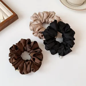 Effen geplooide haarscrunchie in detail met zachte satijnstof en een prachtig hangertje.