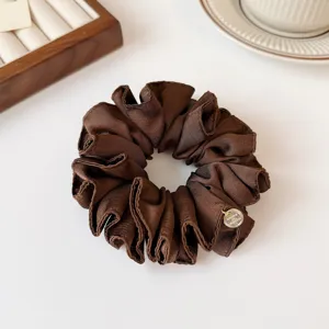 Elegante donkerbruine satijnen haarscrunchie met gouden metalen bedel, zacht haaraccessoire.