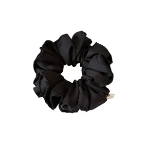 Elegante zwarte stoffen scrunchie met gouden metalen bedel, perfect voor dagelijkse haarstyling.