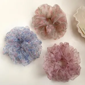 Nahaufnahme von floralen Organza Haargummis mit transparentem Stoff und zarten Pastelltönen.