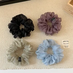 Close-up detail of sheer organza hair scrunchies in multiple colors, soft lightweight fabric.