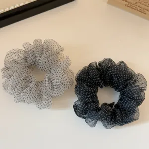 Close-up view of elegant sheer organza hair scrunchies featuring classic polka dot patterns.