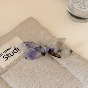 Elegante pinza de pelo con lazo de acetato y patrón de mármol morado, estilo chic y moda.