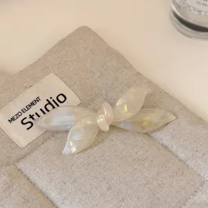 Detalle de pinza de pelo con lazo de acetato blanco perlado exquisito, diseño elegante.