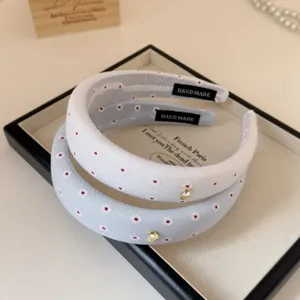 Detail view of sweet daisy embroidered fabric headband with sparkling crystal heart charm.