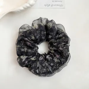 Detail view of a black floral organza hair scrunchie with rhinestones, fluffy and stylish.