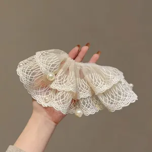 Close-up detail of off-white lace pearl scrunchie, soft ruffled mesh hair accessory.