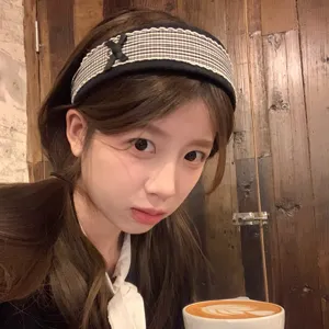 Detailed shot of a stylish black and white plaid wide headband with cute bow, worn in cafe scene.