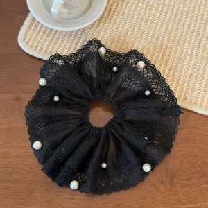 Detailed shot of elegant black lace hair scrunchie decorated with pearls for women styling.