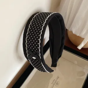 Close-up detail of black and white polka dot lace headband with bow and delicate lace trim.