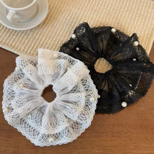 Close-up view of elegant black and white lace hair scrunchies decorated with pearls, detail.