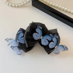 Detailaufnahme einer schicken schwarzen Haarklammer mit Schleife und blauen Schmetterlingen.
