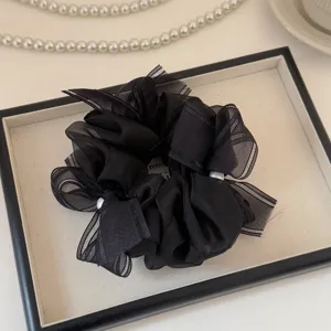 Gros plan détail du chouchou en filet noir avec perles délicates et ruban nœud.