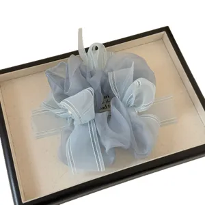 Chouchou en organza bleu avec longs rubans et perle, accessoire de coiffure élégant et léger.