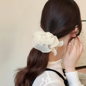 Detailopname van een elegante ecru geplooide mesh haarelastiek gedragen in een paardenstaart.