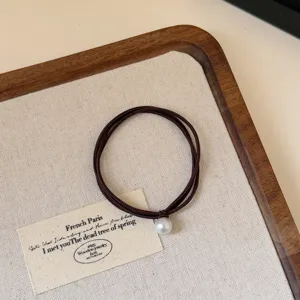 Detail shot of elegant French style dark brown pearl hair tie, minimalist chic accessory.
