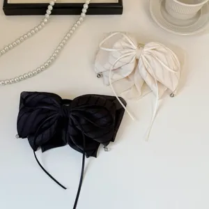Gros plan de pinces à cheveux élégantes avec nœuds rayés en noir et blanc en tissu léger.
