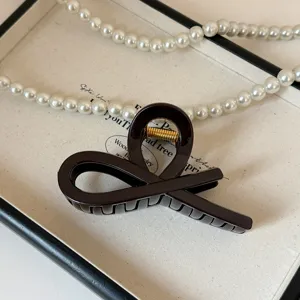 Elegante molletta per capelli in acrilico marrone scuro con design incrociato chic.
