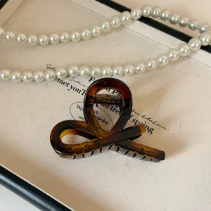 Molletta per capelli in acrilico tartaruga, elegante design a cappio incrociato per acconciature.