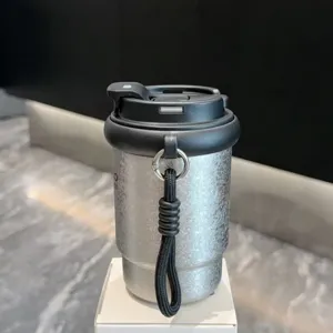 Portable stainless steel coffee cup vacuum insulated travel mug with handy strap detail.