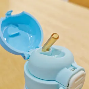 Close-up detail of blue thermos cup lid with straw and open mechanism for daily drinking.