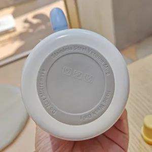 Vista dettagliata del fondo della tazza termica con istruzioni di cura e simboli.