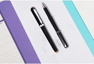 Close-up detail of black gel rollerball pens with silver clip on stationery background.