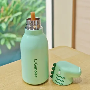 Stainless steel insulated water bottle with cute dinosaur straw cap detail on wooden table.