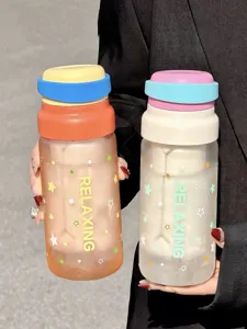 Gros plan de la bouteille d'eau en verre dépoli avec couvercle coloré et motif d'étoiles.
