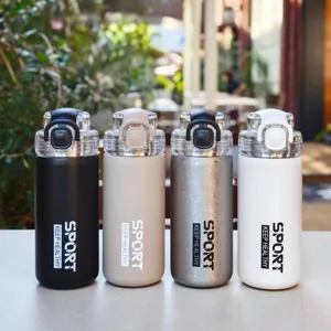 Close-up detail of four colorful insulated sport water bottles with straw lids on café table.