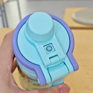 Vista dettagliata del coperchio della borraccia spray portatile, design blu e viola per sport.