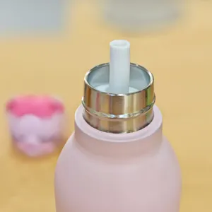 Stainless steel thermos bottle detail, pink vacuum cup with internal white straw component.