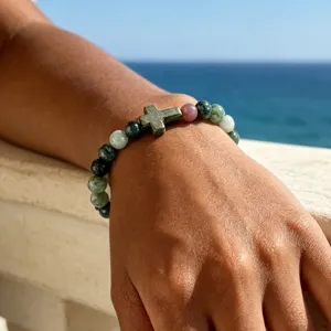 Close up of beaded stone cross bracelet detail, handmade elastic wrist jewelry.