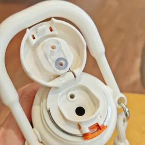 Detailed view of portable insulated water bottle lid with straw valve, push lock, and handle.