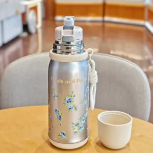 Stainless steel vacuum water bottle detail, featuring blue floral pattern, silver finish and portable strap.