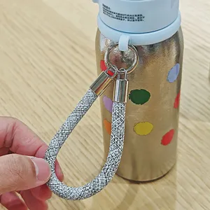 Bouteille d'eau isotherme en titane léger avec motifs colorés et sangle tressée pratique.